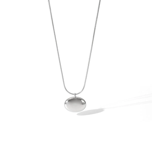 Détail en gros plan d'un collier avec pendentif en forme de fève en acier inoxydable poli