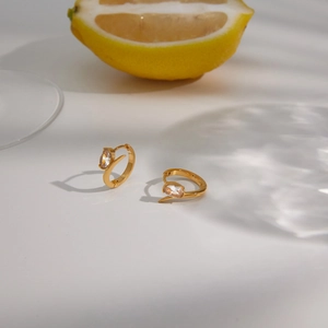 Close-up of elegant gold stainless steel hoop earrings with clear oval zircon detail