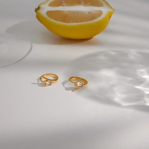 Close-up of elegant gold stainless steel hoop earrings with clear oval zircon gemstone