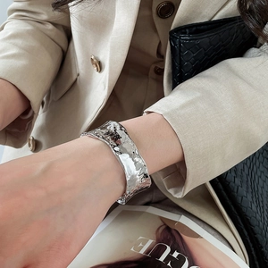 Primo piano di un ampio bracciale rigido argento con trama a canna di bambù