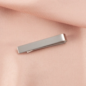 Detailed close-up view of a minimalist silver stainless steel tie clip with brushed finish