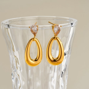 Detalle de pendientes de acero dorado con circonita cúbica en forma de gota.