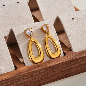 Detalle de elegantes pendientes de gota en acero inoxidable dorado con circonitas claras.