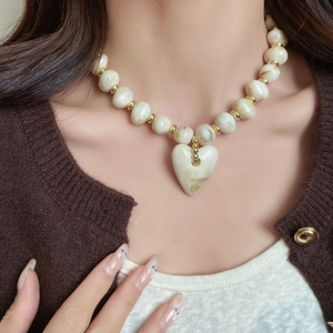 Detailaufnahme einer böhmischen Perlenkette mit marmoriertem Herzanhänger am Model