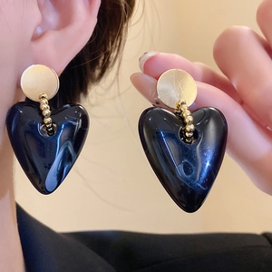 Detailansicht der schwarzen Acryl-Ohrringe in Herzform mit goldenem Stecker für Damen