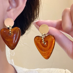 Nahaufnahme von böhmischen Bernsteinharz Herzohrringen mit eleganten goldenen Perlen