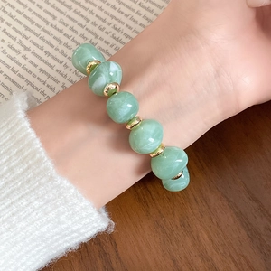 Nahaufnahme eines vintage hellgrünen Acryl-Perlenarmbands mit Marmor-Textur am Handgelenk.