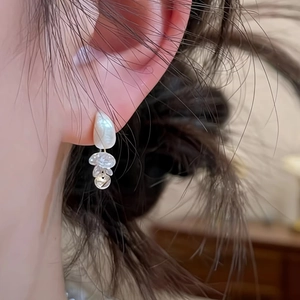 Detailed view of silver brushed teardrop earring with zirconia tassels on ear