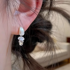 Detailed close-up showing silver brushed teardrop earrings with zircon tassels worn on ear