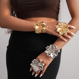 Detailed view of metallic ruffled flower bracelets and rings in gold and silver finish
