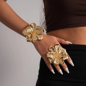Close-up detail of oversized gold metallic wrinkled flower bracelet and ring set on model