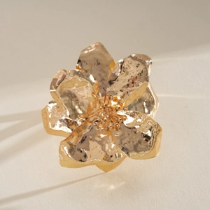 Detailed macro view of an oversized gold-finished metallic flower ring with pleated petals