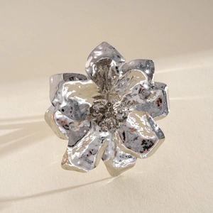 Detailed close-up of a silver metallic crumpled flower ring with hammered texture