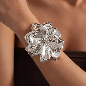 Exquisite detail of a large silver metallic wrinkled flower cuff bracelet on arm.