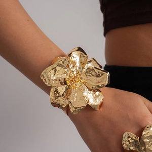 Detailed view of gold metallic flower cuff bracelet and matching ring on model