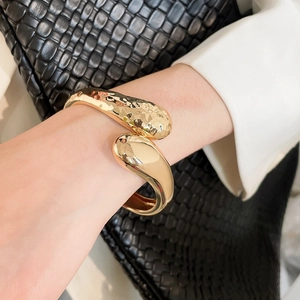 Détail d'un bracelet en métal doré torsadé irrégulier avec finitions martelées et polies