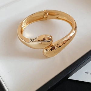 Gros plan détaillé montrant les textures martelées et lisses du bracelet en métal doré irrégulier