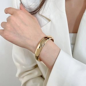 Vue détaillée d'un élégant bracelet rigide en métal doré torsadé porté au poignet du mannequin