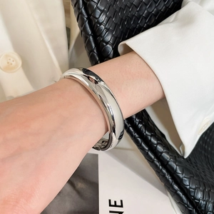 Gros plan d'un bracelet jonc en métal argenté torsadé avec finition miroir polie