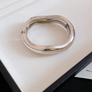 Vue détaillée d'un bracelet en métal argenté aux formes irrégulières sur un plateau