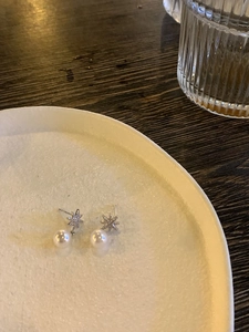 Close-up detail of silver star snowflake earrings with white pearls and cubic zirconia
