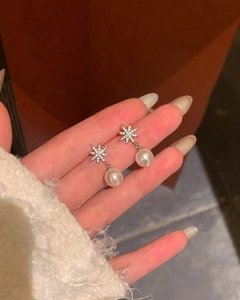 Detail view of elegant starburst pearl earrings with sparkling zircon accents on hand.