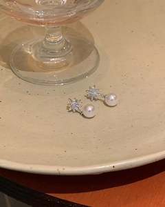 Macro view of eight-pointed star zircon earrings with elegant hanging white pearls
