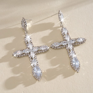 Nahaufnahme von funkelnden Kreuzohrringen mit Zirkonia und feinen Silbernadeln.