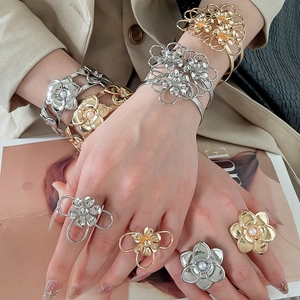 Dettaglio ravvicinato di grandi bracciali e anelli a fiori in metallo sulle mani della modella