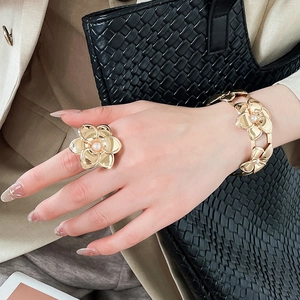 Dettaglio di un set lussuoso bracciale e anello con fiori in metallo su una modella