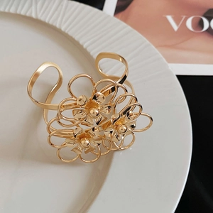 Dettaglio ravvicinato di un lussuoso bracciale aperto in oro con triplo motivo floreale