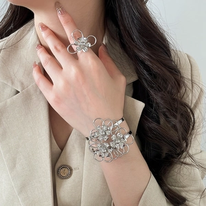 Dettaglio macro di un set bracciale e anello a fiore cavo argento su una modella