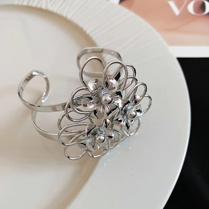 Dettaglio di un bracciale a polsino in metallo argentato con fiori traforati chic