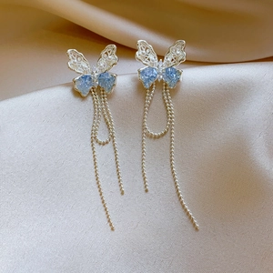 Primo piano di eleganti orecchini a farfalla argentati con pietre blu e nappine lunghe.