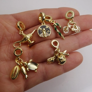 Golden micro-pave charms with candy and globe shapes shown on hand for size