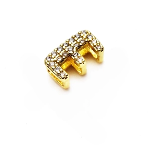 Detalle macro de un dije letra E bañado en oro de 14K con piedras de circonita