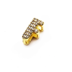 Detalle del dije letra F bañado en oro de 18K con incrustaciones de circonitas brillantes