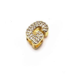 Detalle de un dije de letra G dorado con circonitas brillantes para pulseras