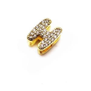 Vista detallada del abalorio en forma de H dorado con micro-pavé de circonitas brillantes