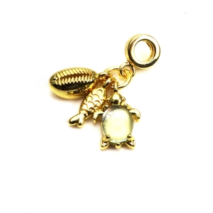 Detail view of gold-tone charm pendant with turtle and fish motifs for charm bracelets