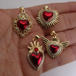 Ensemble de pendentifs Coeur Sacré en émail rouge et cristaux présenté sur la main