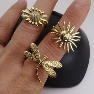 Juego de tres anillos dorados con motivos de sol, girasol y libélula con circonitas