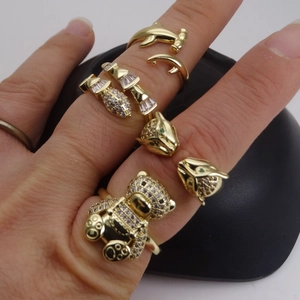 Vista de detalle de anillos de cabeza de leopardo y oso dorados con circonitas micro-pave