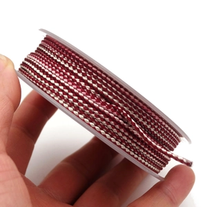 Macro detail of 1.5mm two-tone dragon pattern woven cord for DIY jewelry on a clear spool