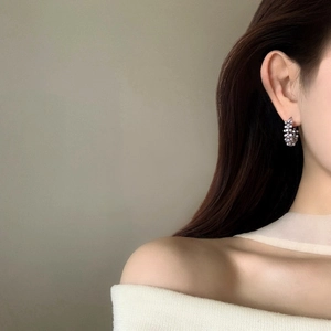 Vue détaillée de profil d'une élégante boucle d'oreille créole en perles portée par un modèle