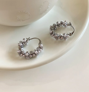 Gros plan de créoles en perles rétro avec grappes de perles sur une assiette blanche