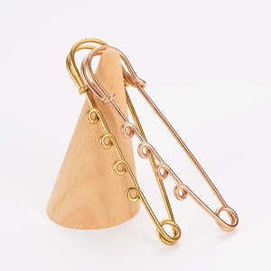 Close-up of 18k gold and rose gold plated decorative safety pins on wood.