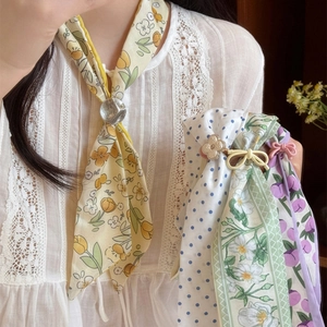Close-up of floral and polka dot silk scarves with decorative buckles.