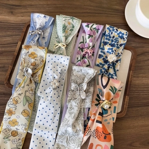 A variety of colorful floral and polka dot silk scarves with elegant metal buckles on a tray