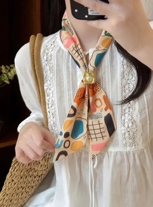 Detailed view of an abstract geometric patterned silk scarf with a gold pearl slider